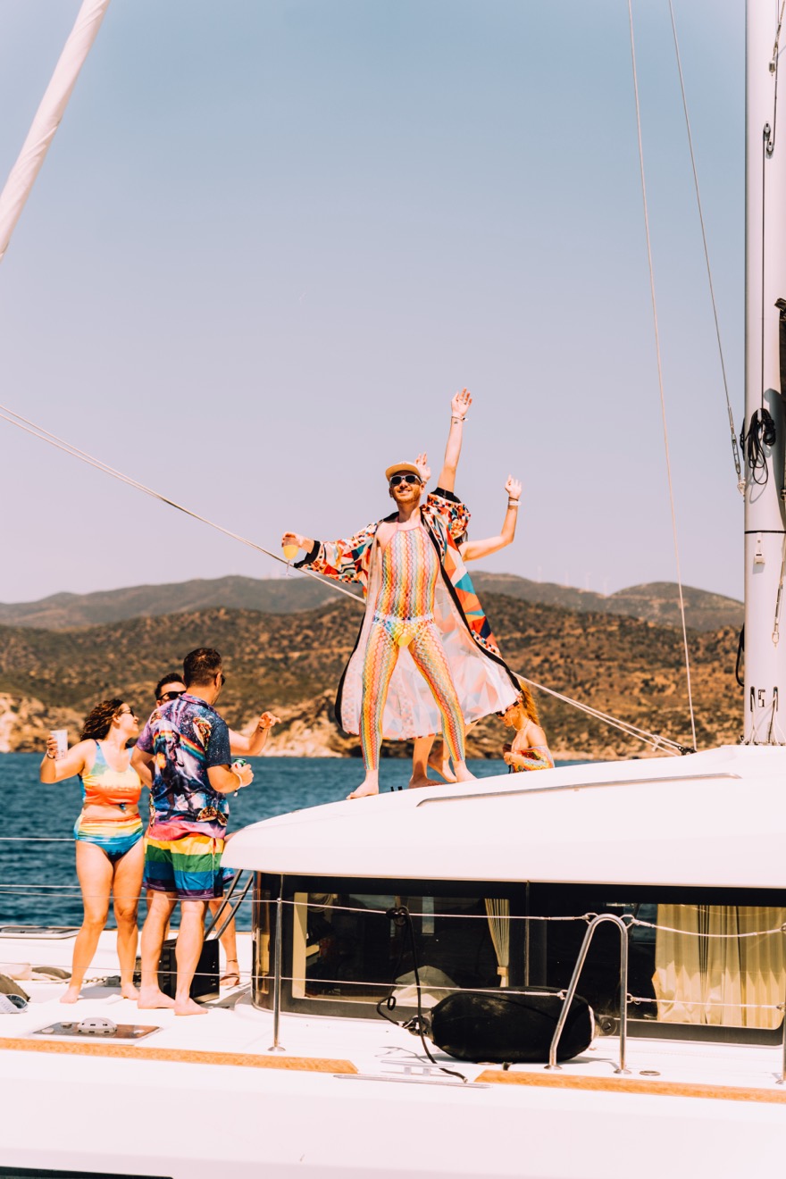 Guests in colourful outfits dancing on the deck of a Yacht Week catamaran